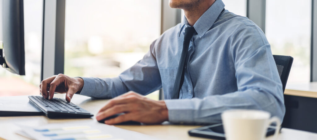 Handsome confident businessman relaxing looking at technology of desktop computer monitor while sitting on chair.Young creative coworkers business people working and typing on keyboard at office